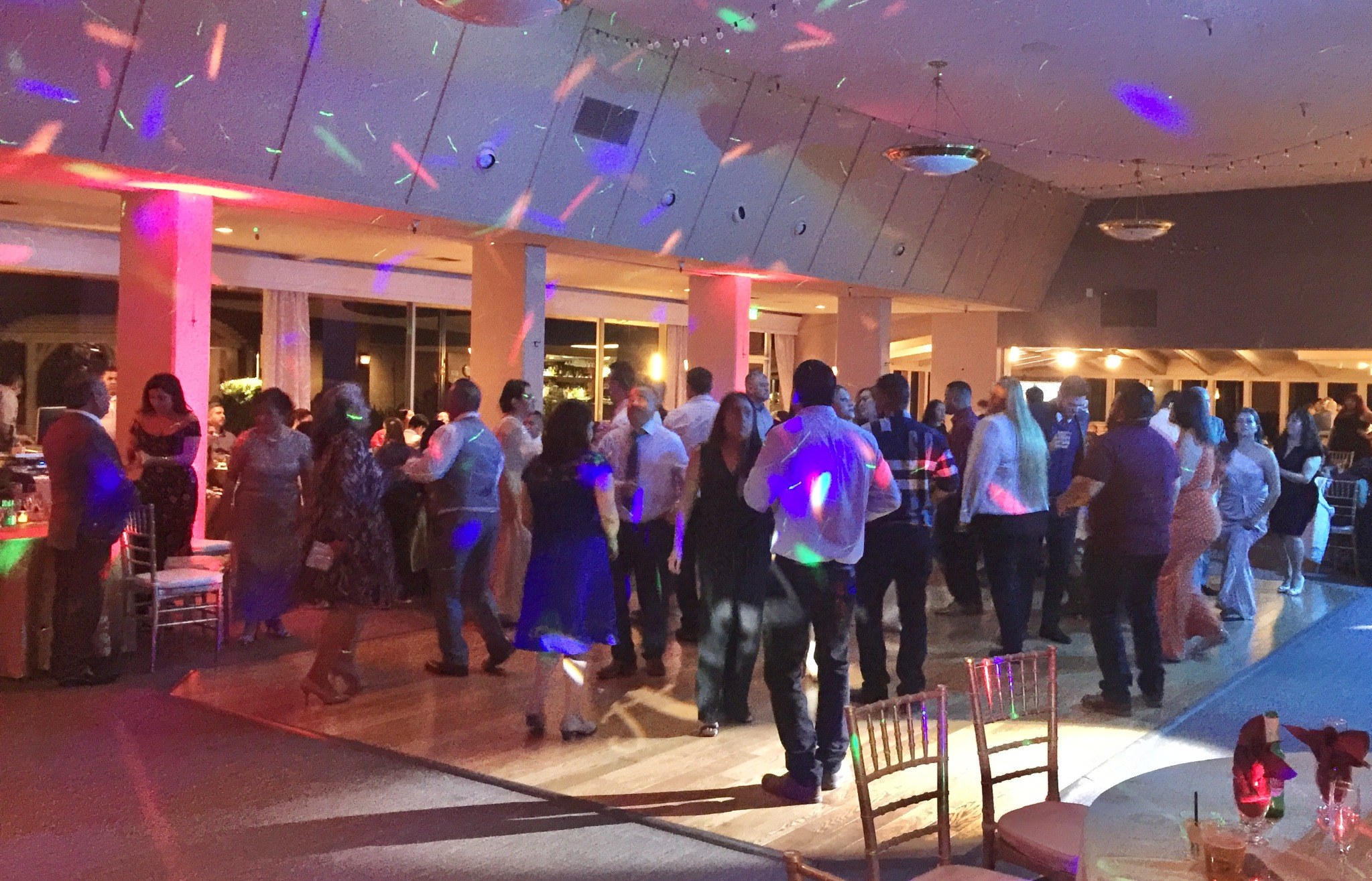 Guests dancing in a reception room with colorful lighting
