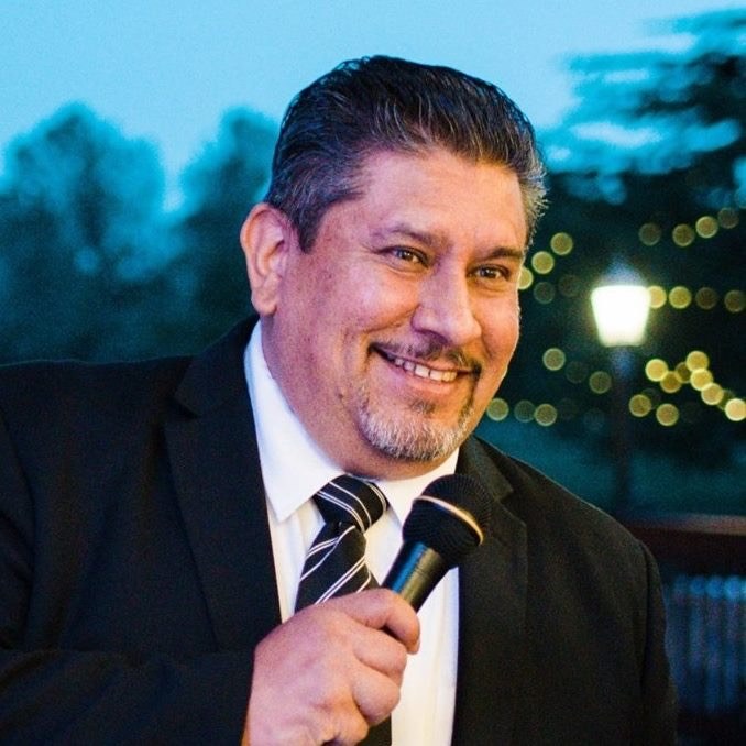 Rey smiling while holding a microphone at an event